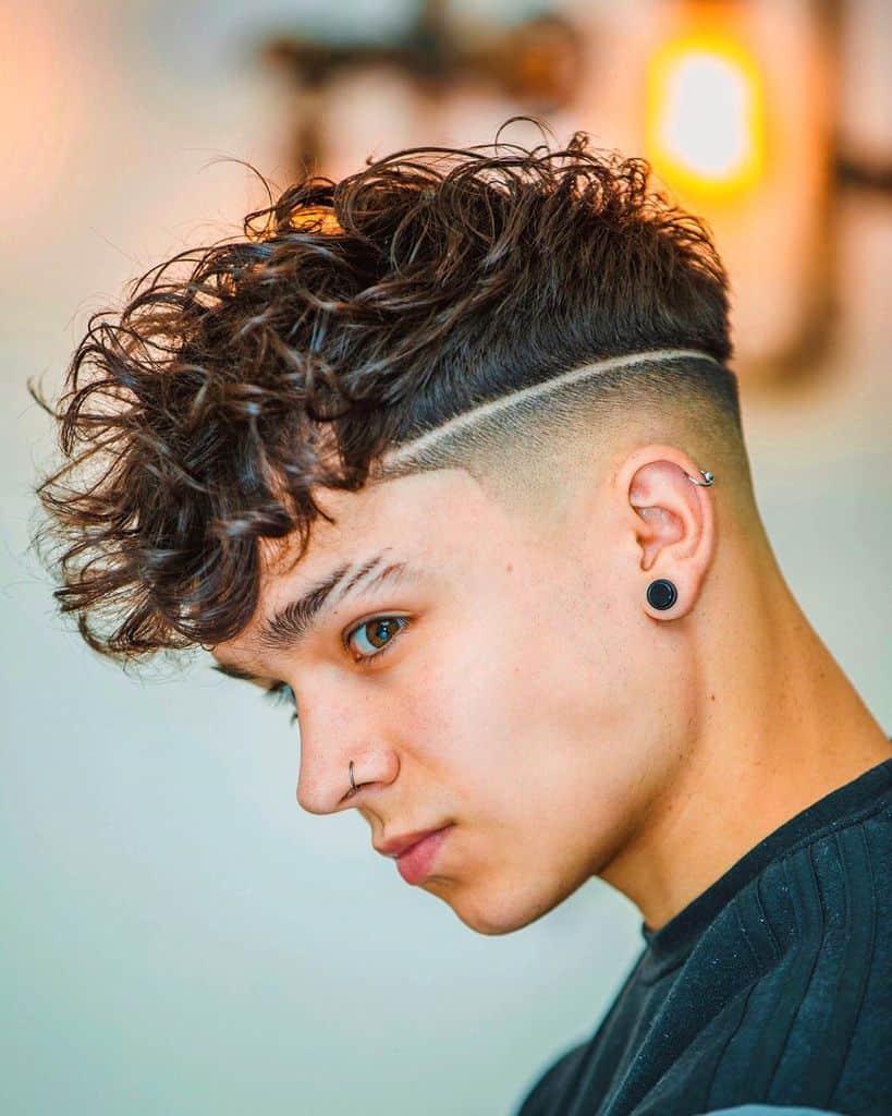 A burst fade haircut featuring a low fade and long curly hair on top