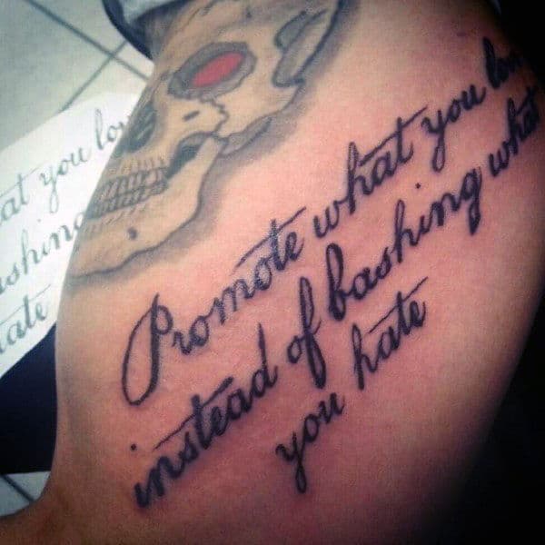 Tattoo on an arm reading "Promote what you love instead of bashing what you hate"