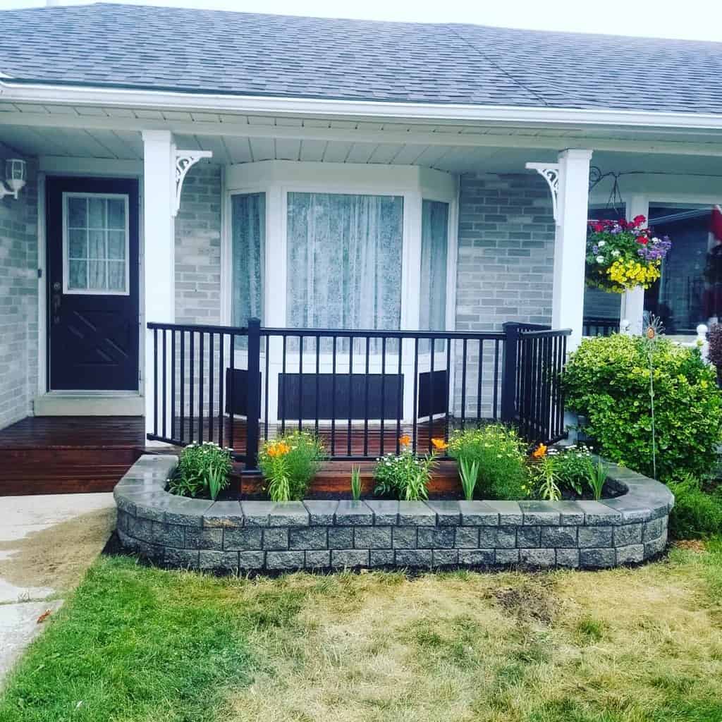 curved stone garden wall wood deck front patio black railing fence