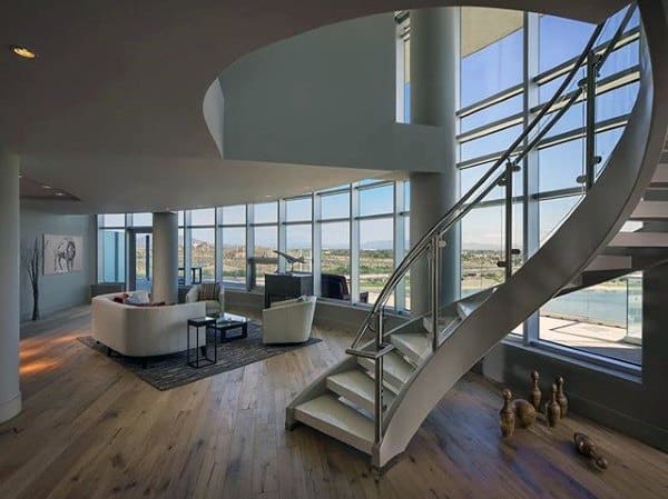 Modern loft with a spiral staircase, large windows, and a cozy seating area overlooking a cityscape
