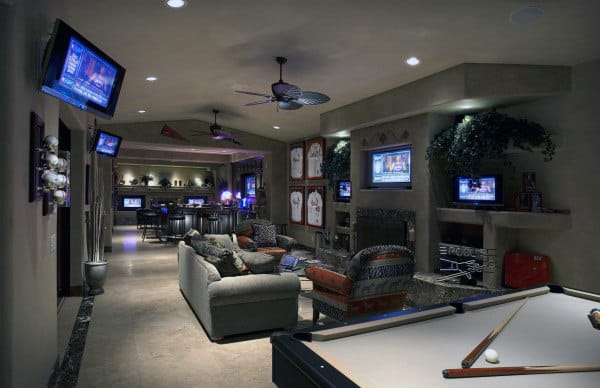 Cozy media room with multiple TVs, a pool table, and comfortable seating; sports memorabilia adorns the walls
