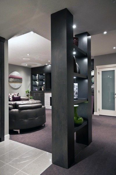 Modern basement with custom black shelf pole, recessed lighting, and sleek decor accents.