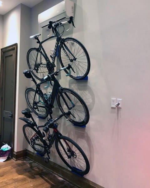 Vertical wall-mounted bike storage with three bicycles stacked neatly, maximizing space and maintaining a clean, organized look.