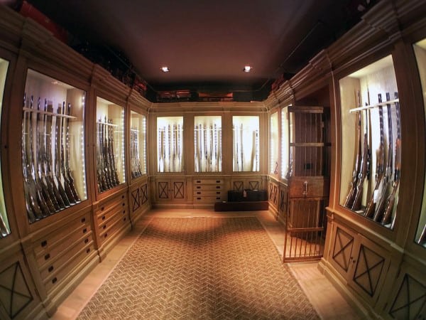 Sophisticated gun room with custom illuminated cabinets, wooden detailing, and a plush patterned rug.