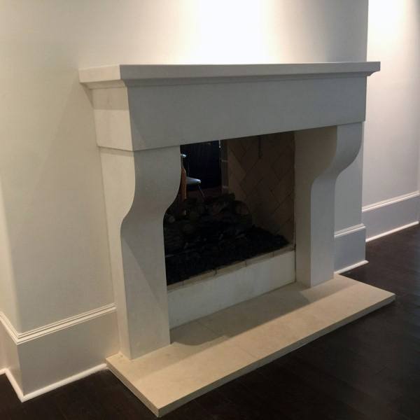 Elegant cast concrete fireplace with curved corbels, herringbone firebox, and classic mantel design.