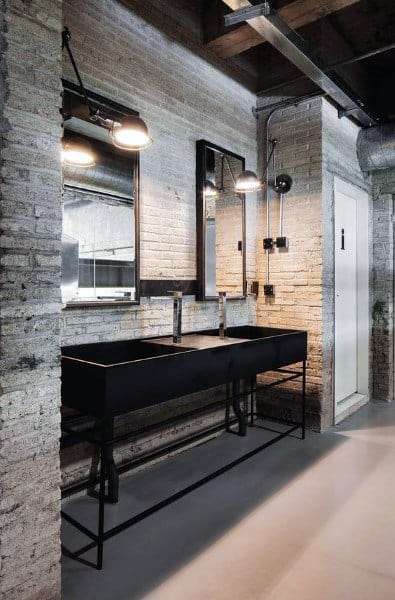 Industrial-style bathroom with exposed wood beams, brick walls, and black double sink vanity.