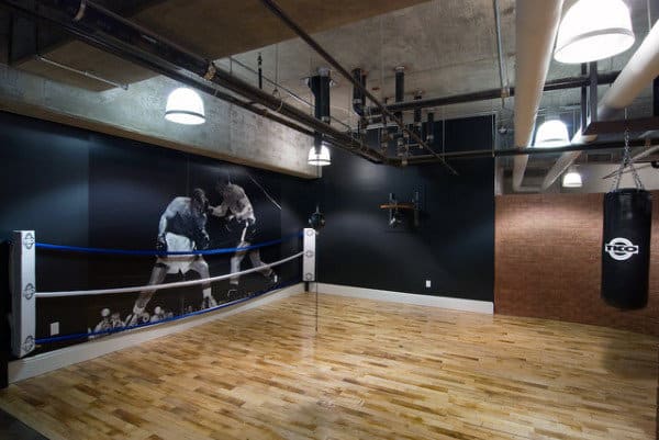 Home boxing-themed room with a mural, a hanging punching bag, and a section of boxing ring ropes
