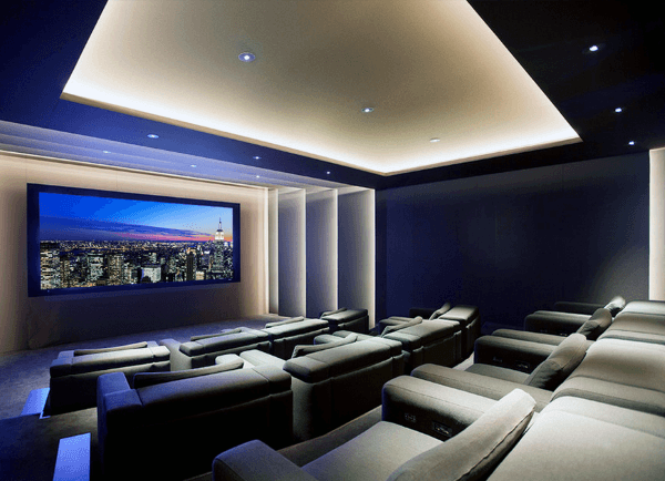 Modern home theater with plush seating and a large screen displaying a stunning cityscape