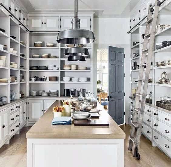 Spacious custom kitchen pantry with open shelving, a central island, and a sliding ladder.