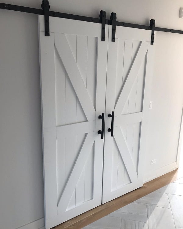 White double sliding barn doors with black hardware in a modern interior hallway.