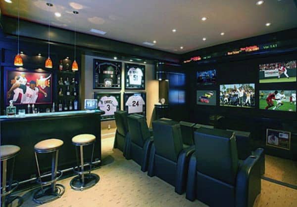 Home theater with sports jerseys, multiple screens, a well-stocked bar, and cozy theater seating