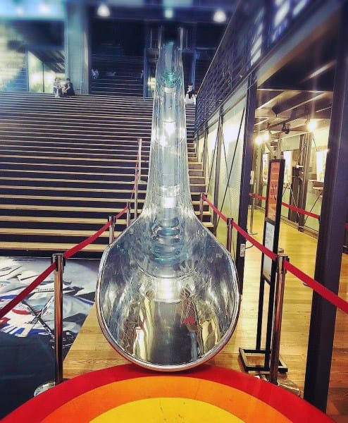 A shiny, curving slide descends from the staircase, red ropes guiding the path at the bottom