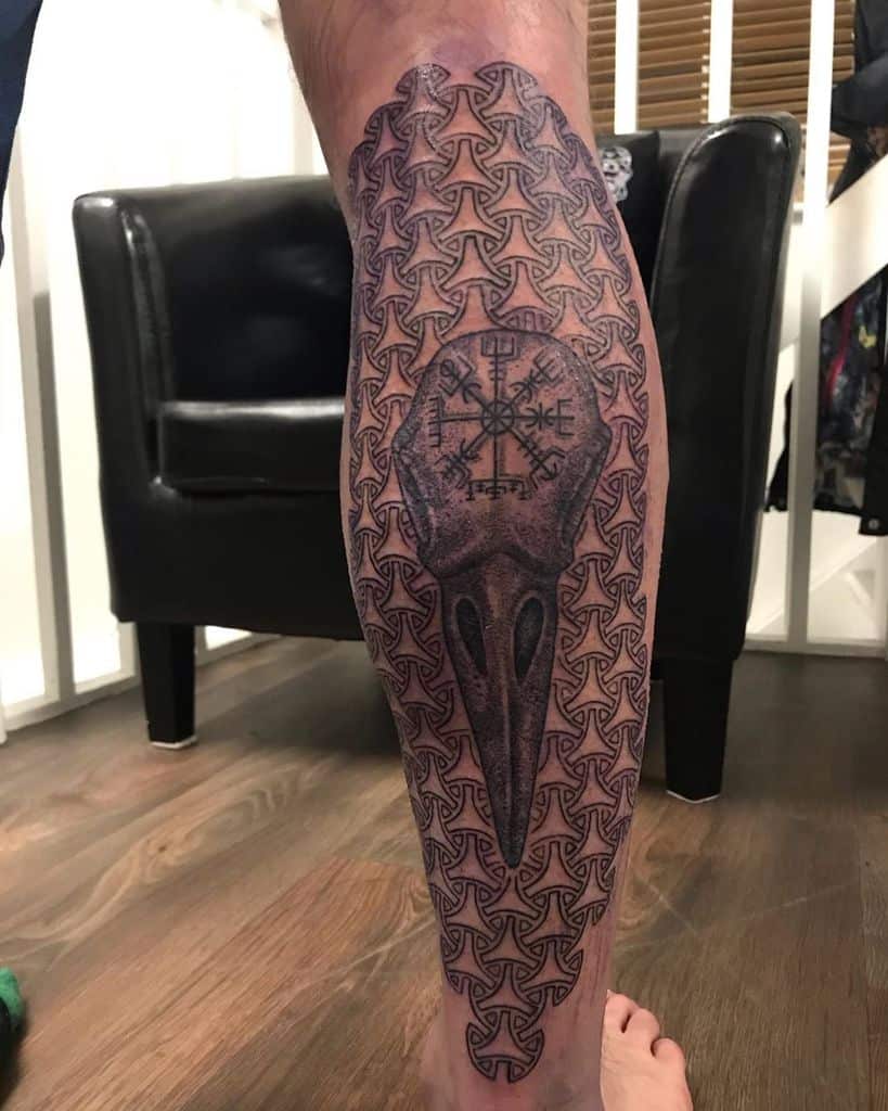 Detailed leg sleeve tattoo featuring a bird skull surrounded by intricate geometric patterns, creating a bold and striking design