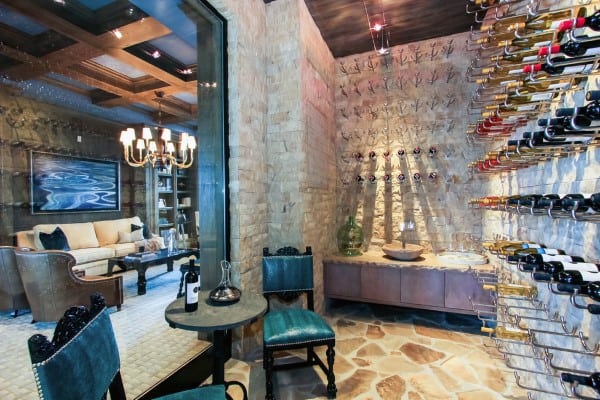 A cozy wine cellar with wall racks, a small table set for wine tasting, adjacent to a stylish living room