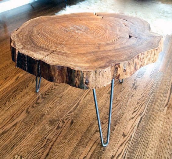 Wooden coffee table with a round tree slice top and metal hairpin legs on a wooden floor