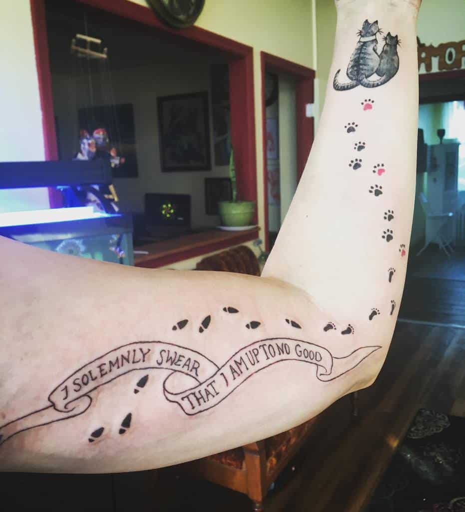 Harry Potter-themed tattoo featuring the Marauder’s Map quote 'I solemnly swear that I am up to no good' with footsteps, paired with cat paw prints leading to two cuddling cats