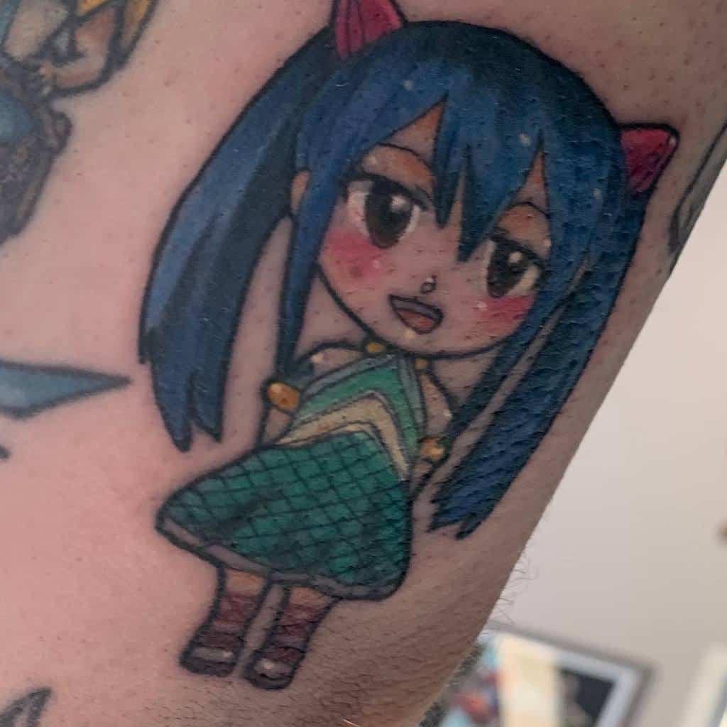 Chibi-style tattoo of Wendy Marvell from Fairy Tail, featuring bright blue hair, red ribbons, and a cheerful expression in a colorful design.