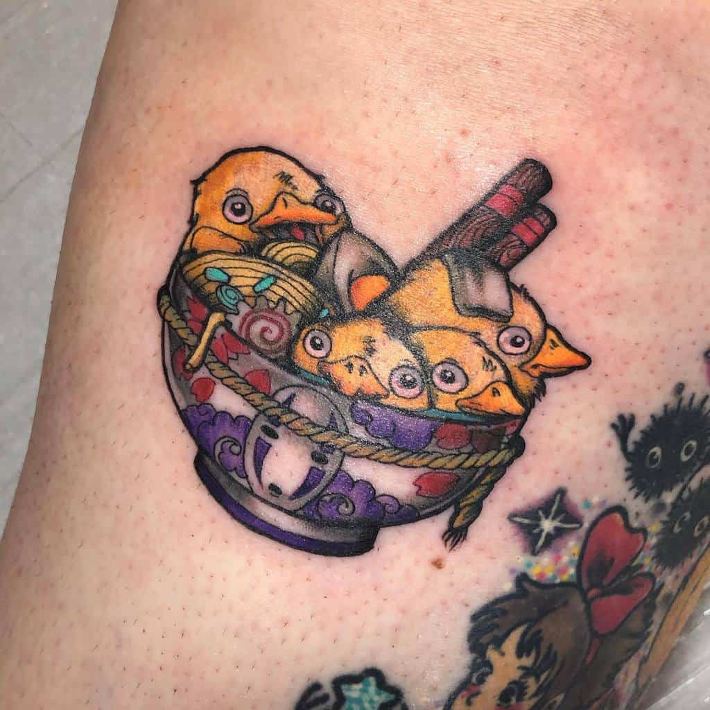 Colorful tattoo of Spirited Away's bird and soot sprite chicks inside a ramen bowl with No-Face details, featuring chopsticks and rope accents