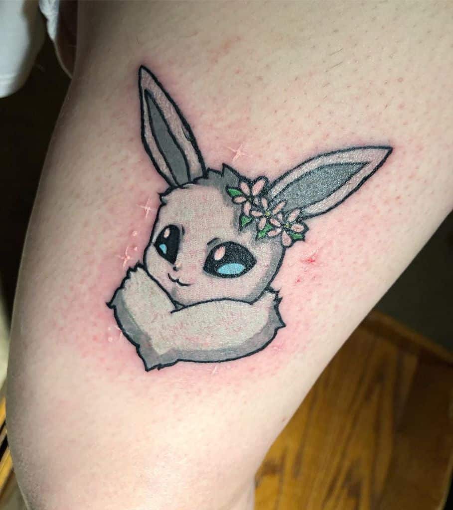 Adorable Eevee tattoo with a delicate flower crown, featuring soft colors and a charming expression