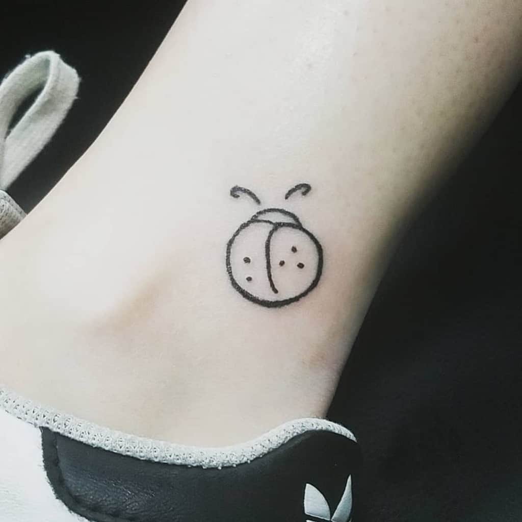 Minimalist ladybug tattoo with a simple, clean line-art design, featuring a round shape and delicate antennae for a cute and subtle look.