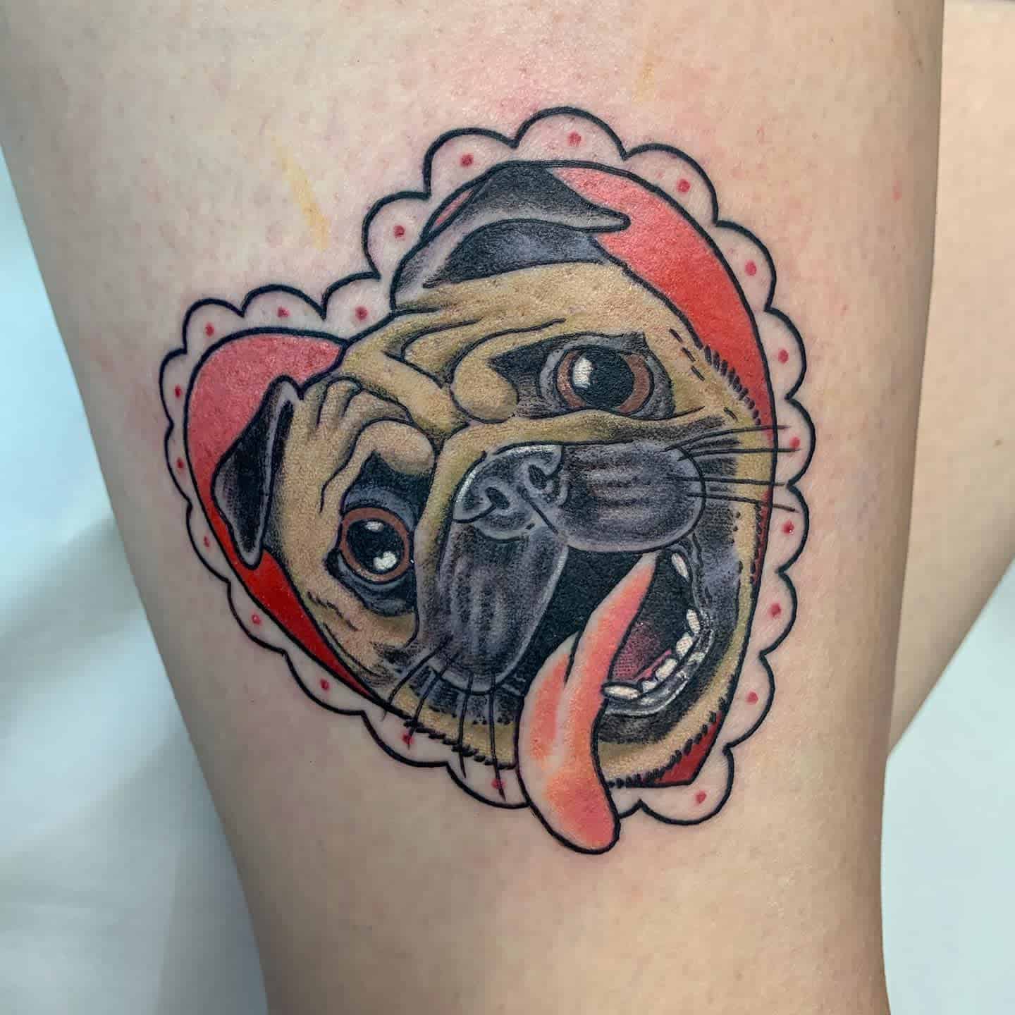 Tattoo of a pug with its tongue out inside a red, scalloped heart design