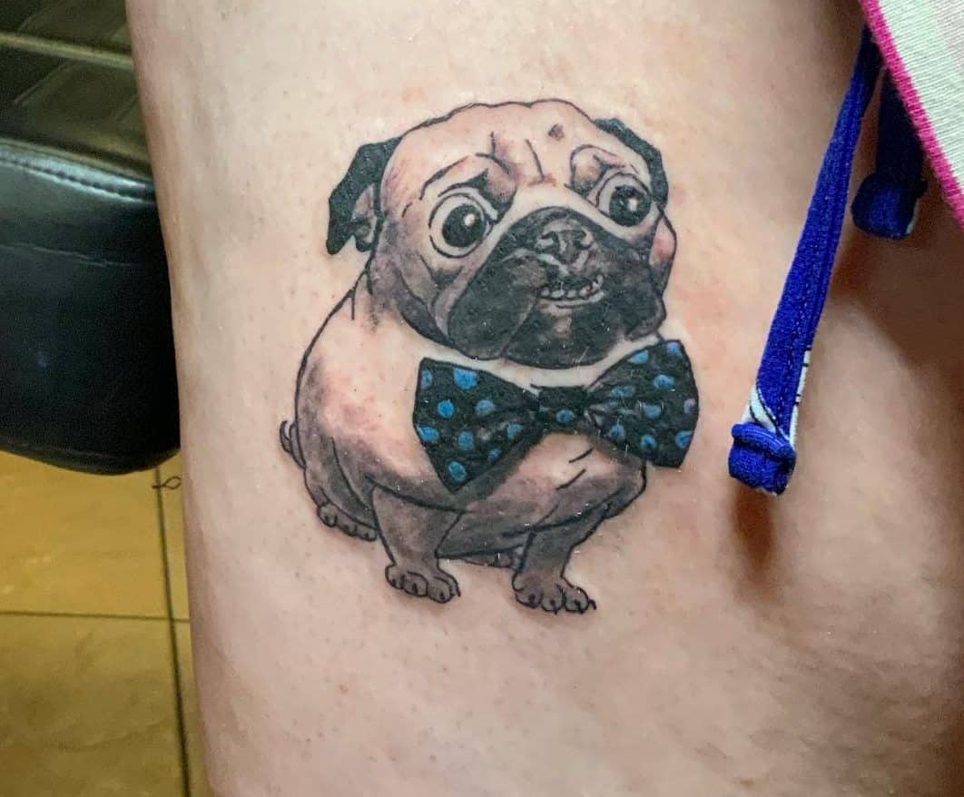 Tattoo of a cartoon pug wearing a blue polka dot bow tie 