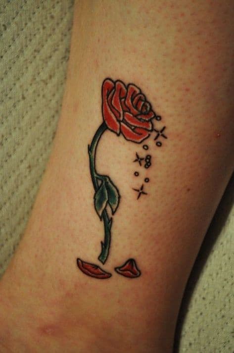 Minimalist enchanted rose tattoo with a delicate stem, sparkles, and falling petals, inspired by Beauty and the Beast.