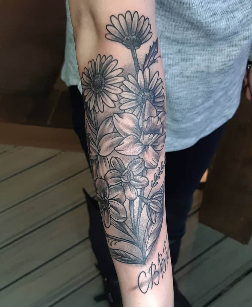 Forearm tattoo large black and grey shading daffodil larkspur daisy with script