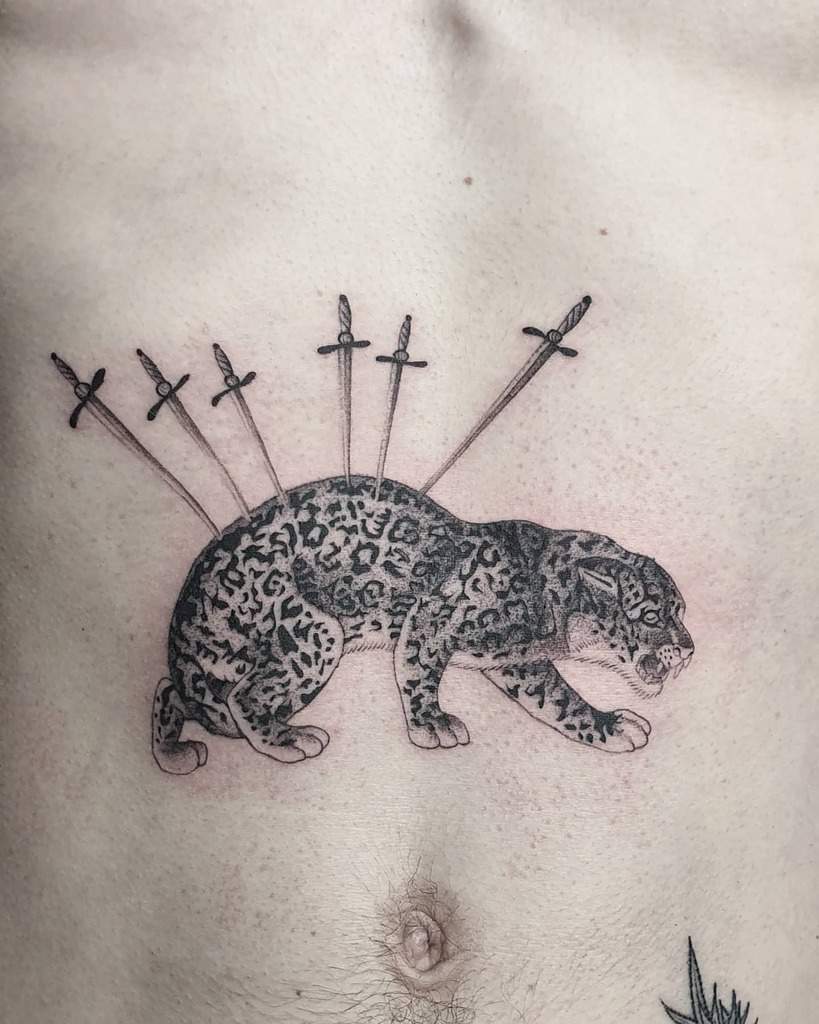 A striking black and grey tattoo of a jaguar with swords piercing its back, creating a bold and dramatic design across the chest.
