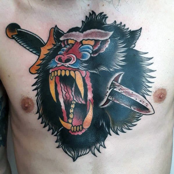 Neo-traditional baboon chest tattoo with bold colors, fierce expression, and dramatic dagger elements for a striking and intense design.