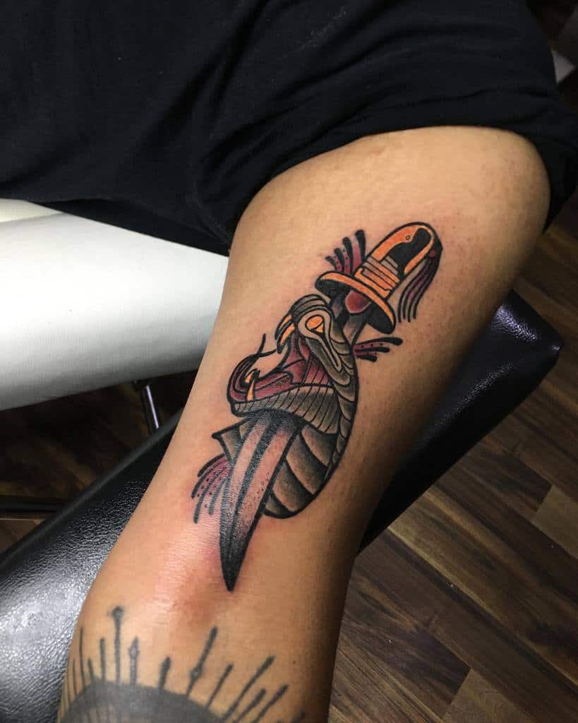 Stylized cobra tattoo wrapped around a dagger on a person's arm