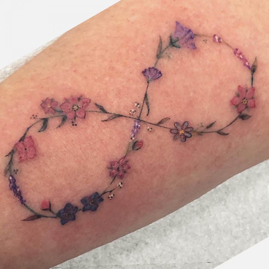 A beautifully delicate infinity tattoo featuring a floral design, with various flowers intertwining to form the symbol of eternity.