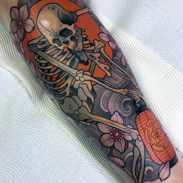 Colorful skeleton tattoo featuring a smoking skeleton with an orange background, floral details, and a lantern, blending bold and artistic elements.