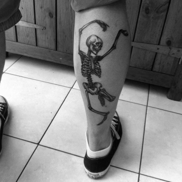 Dancing skeleton tattoo on the calf with fluid movement and raised arms, creating a bold and dynamic look with fine black ink details.