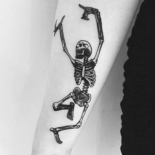 Dancing skeleton tattoo with bold black ink, dynamic movement, and raised arms, creating an energetic and expressive design on the forearm.