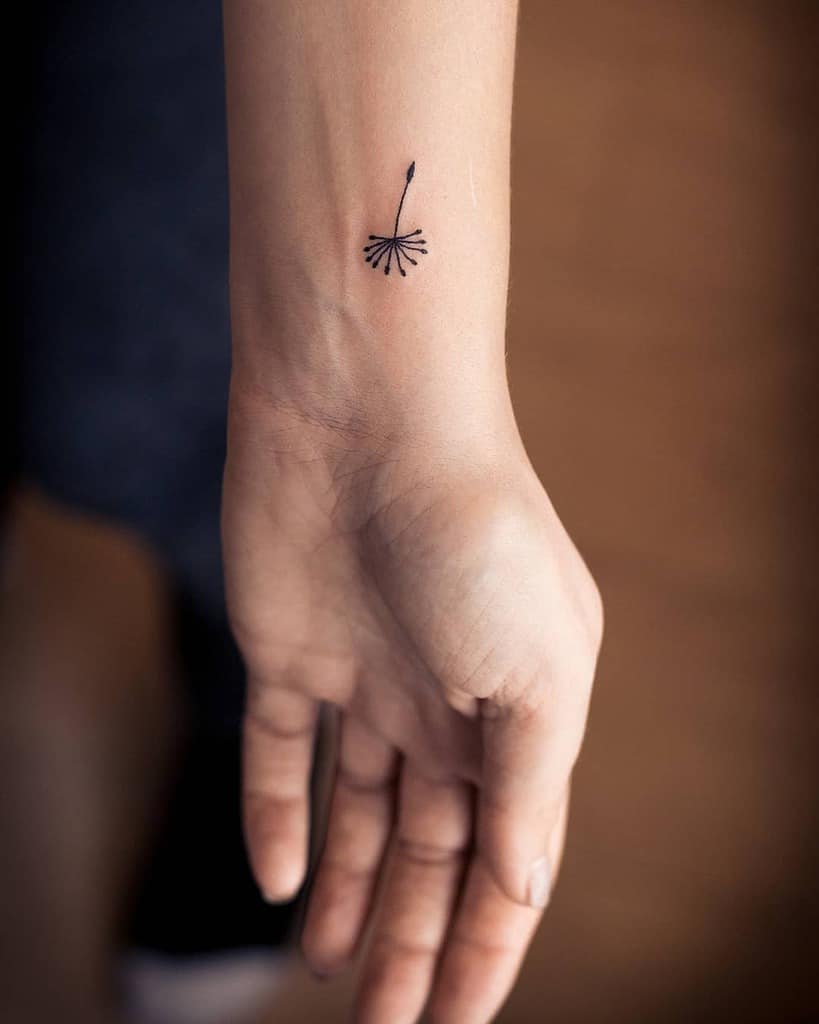 Simple dandelion seed tattoo on the wrist, symbolizing hope, freedom, and new beginnings in a minimalist design.