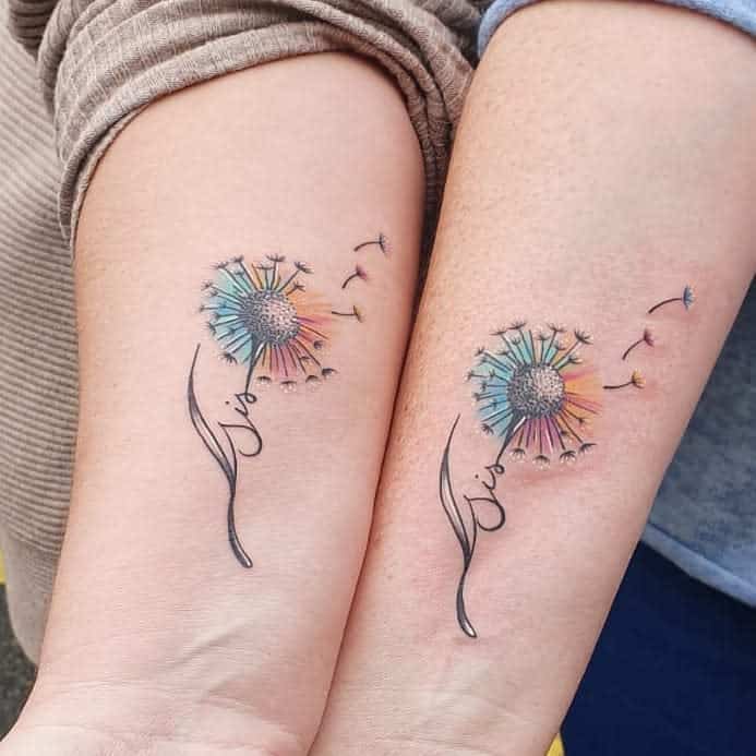 Matching dandelion sister tattoos in colorful hues, with seeds and cursive 'Sis' text below in the stem
