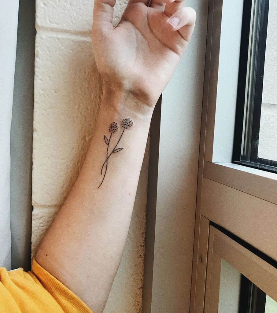 Minimalist dandelion tattoo on the wrist with two delicate flowers and fine-line stems, symbolizing growth, simplicity, and new beginnings.