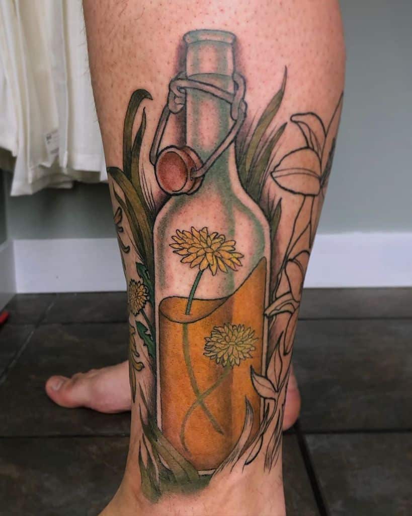 This tattoo features a bottle surrounded by vibrant flowers, possibly symbolizing the concept of nature being contained yet free. The intricate use of color adds depth and life to the design.