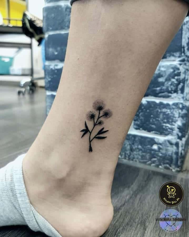 This tattoo features a simple, delicate design of dandelion-like flowers with slender stems. It’s a minimalistic yet elegant tattoo.