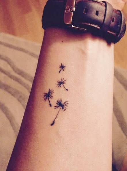 Minimalist dandelion seed tattoo on the wrist, symbolizing freedom, wishes, and embracing life's journey.