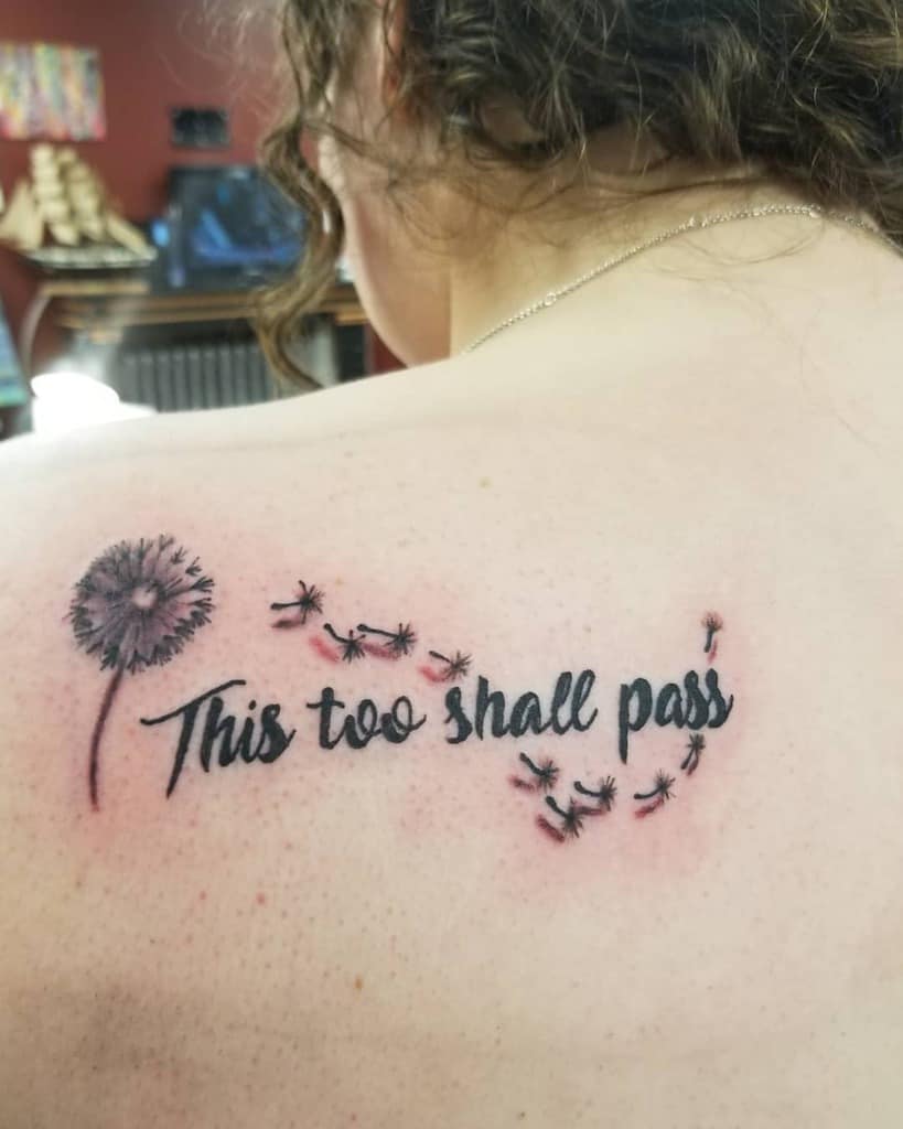 A delicate "This too shall pass" tattoo with a dandelion, symbolizing letting go and resilience.