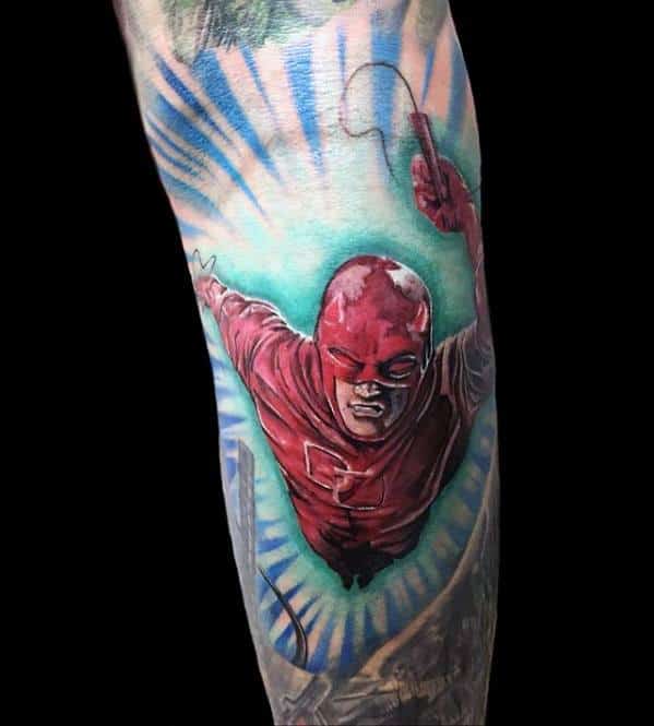 Colorful Daredevil tattoo in mid-air action pose with bright blue rays and bold red suit, capturing a dynamic superhero moment.