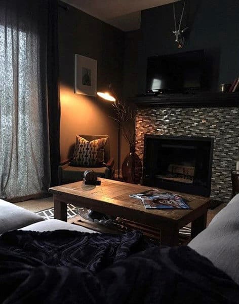 Modern living room with dark tones, a cozy fireplace, and wooden coffee table.