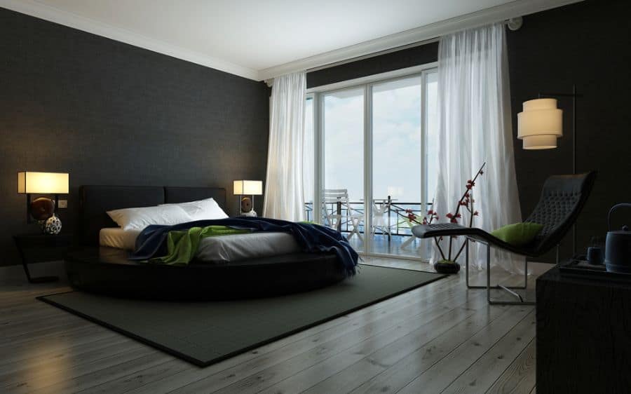 Modern bedroom with black walls, round bed, sheer white curtains, and large windows.