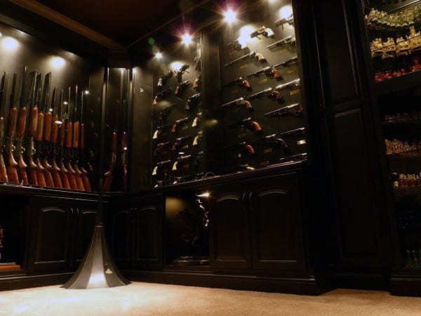 Sophisticated gun room with black wood cabinets, spotlit display cases, and a luxurious ambiance.