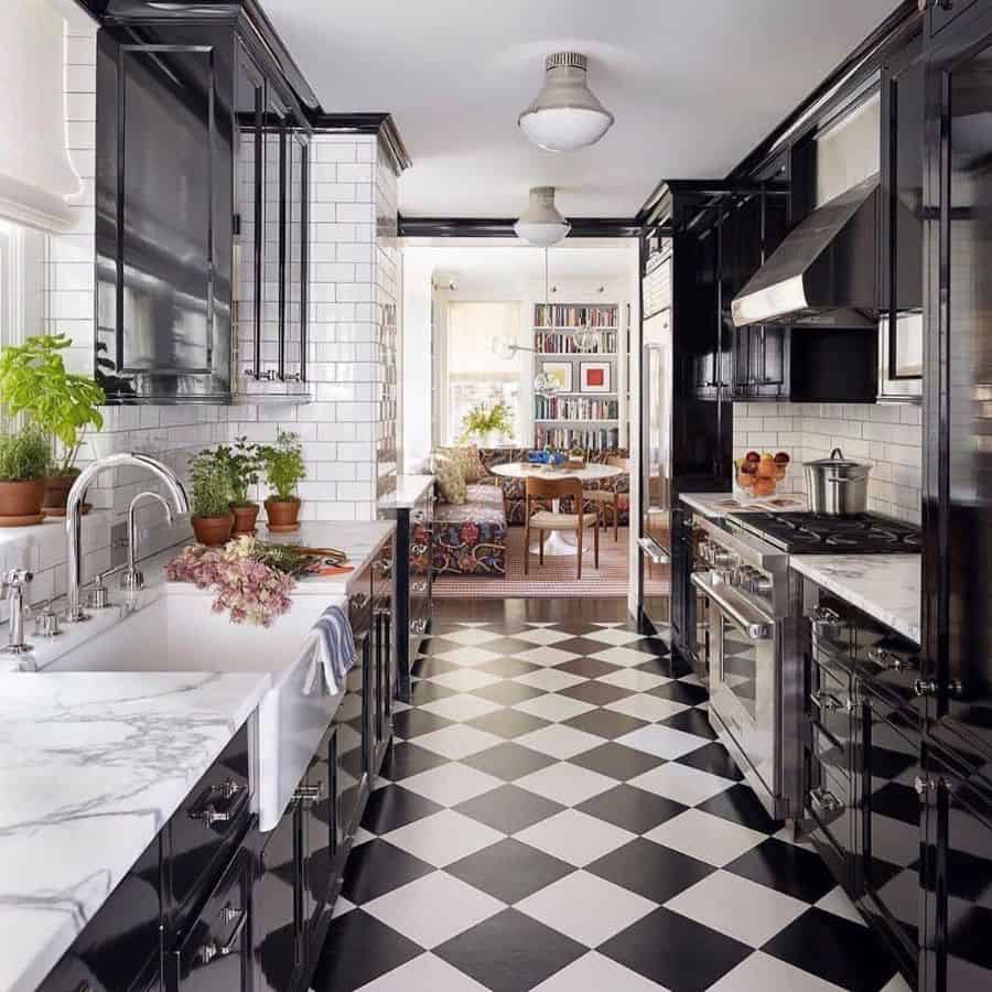Sleek galley kitchen with black cabinets, checkered flooring, and bright subway tiles for contrast.