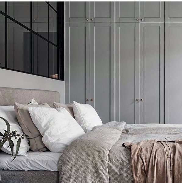 Modern bedroom with grey built-in wardrobe, neutral bedding, and cozy pillows.