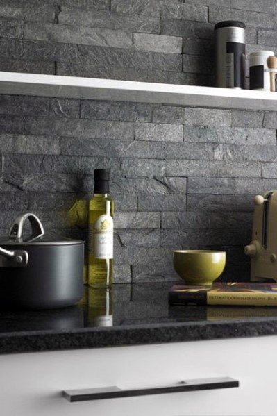 Modern kitchen with a dark grey stacked stone backsplash, sleek black countertop, and minimalist decor accents