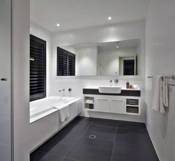 Modern bathroom with dark grey slate flooring, white bathtub, and floating vanity.